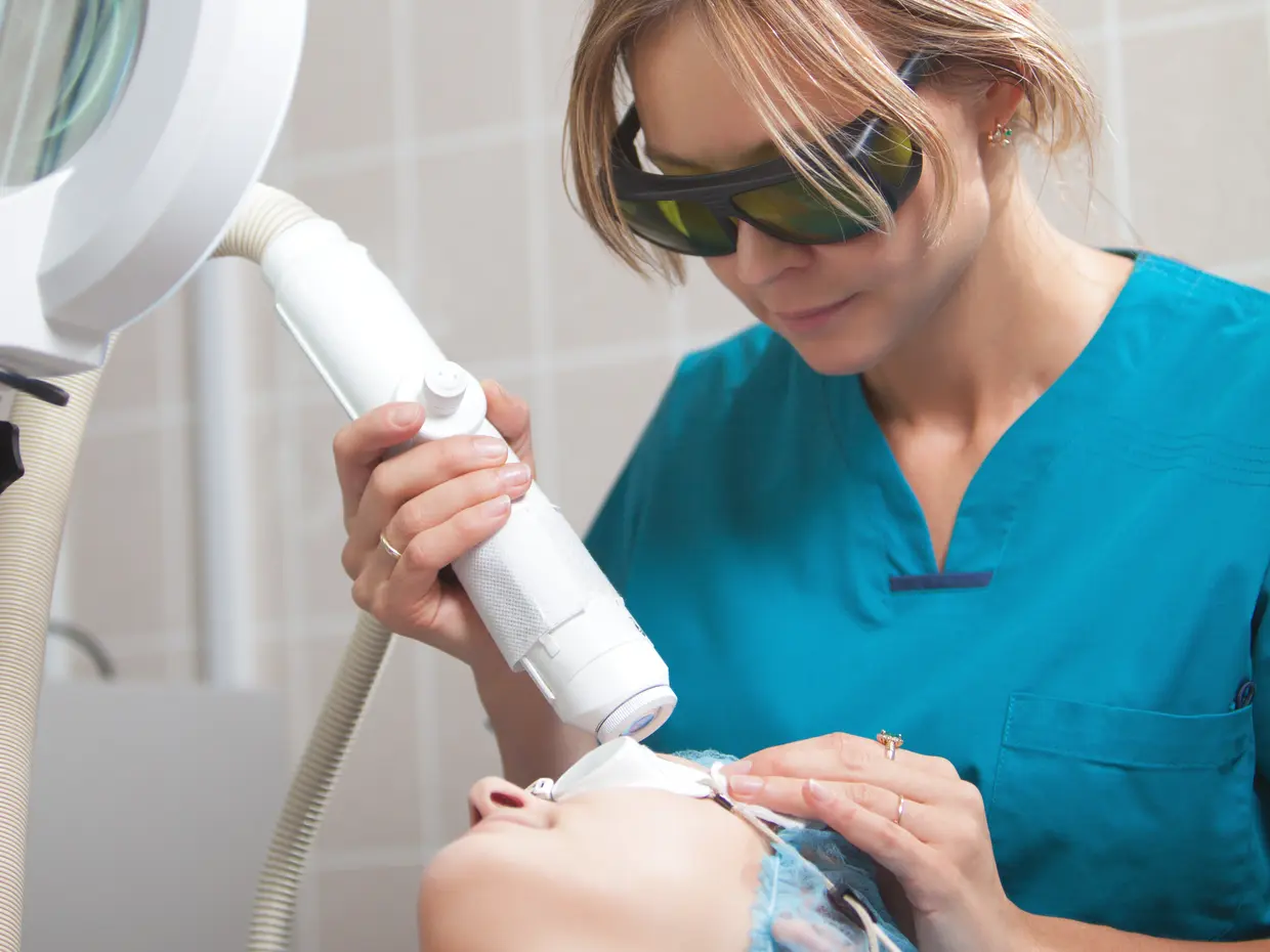 aesthetician performing laser treatment on client's face
