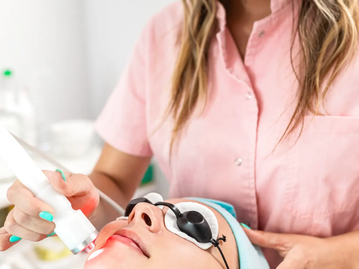 aesthetician performing laser treatment on client's face